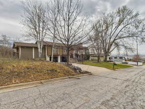 View of front facade featuring concrete driveway and a front lawn