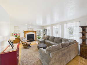Living room featuring a tiled fireplace, light wood-style flooring, and a textured ceiling