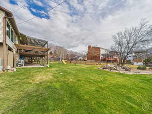 View of yard with a playground, a deck with mountain view, and a patio area