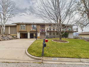 Bi-level home with driveway, a front lawn, and an attached garage