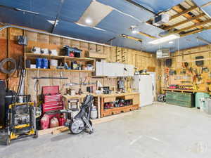 Detached Garage featuring a workshop area, a heating unit, freestanding refrigerator, and a garage door opener