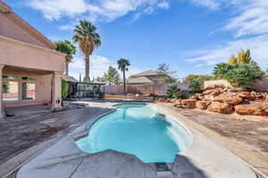 View of swimming pool featuring patio surround and a fenced backyard