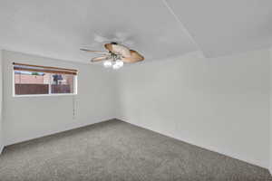 Unfurnished room with a ceiling fan, carpet floors, and a textured ceiling
