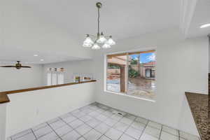 Unfurnished dining area featuring suspended lighting, a ceiling fan, and light tile patterned floors