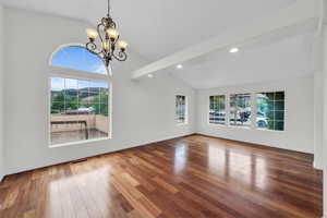 Unfurnished living room featuring vaulted ceiling, wood-type flooring, and a chandelier