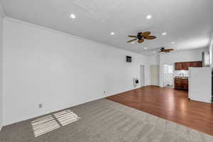 Unfurnished living room with crown molding, dark colored carpet, ceiling fan, recessed lighting, and dark wood-type flooring