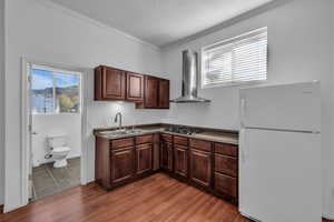 Kitchen with dark countertops, freestanding refrigerator, crown molding, dark wood finish cabinetry, and a textured ceiling