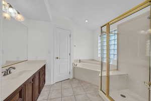 Bathroom featuring vanity, a bath, vaulted ceiling, light tile patterned flooring, and a shower stall