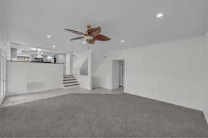 Unfurnished living room featuring crown molding, a ceiling fan, recessed lighting, light carpet, and light tile patterned flooring