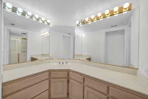 Bathroom featuring vanity, a textured ceiling, and a shower with door