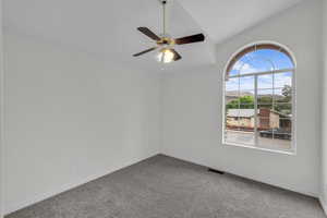 Carpeted spare room with ceiling fan and lofted ceiling
