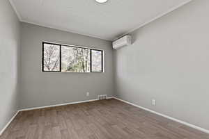 Unfurnished room featuring light wood-type flooring, crown molding, and a textured ceiling