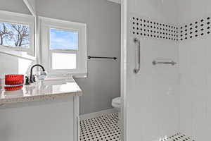 Bathroom with vanity, a tile shower, and light tile patterned floors.