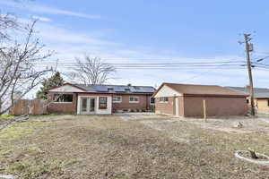 Back of property with solar panels, french doors, brick siding, a patio area, and an outbuilding