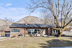 Ranch-style home featuring brick siding, a mountain view, roof with shingles, and a chimney
