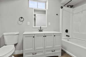 Bathroom with bathtub / shower combination, vanity, and dark wood-style floors