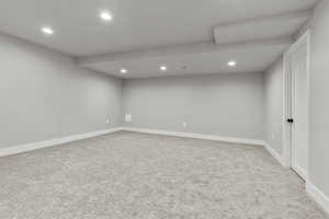 Finished below grade area with recessed lighting and light colored carpet