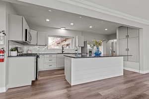 Kitchen featuring dark stone countertops, stainless steel appliances, backsplash, white cabinets, and recessed lighting