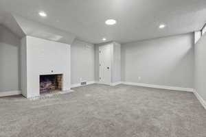 Finished below grade area with a fireplace, light carpet, and recessed lighting