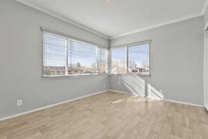 Spare room with light wood-type flooring and crown molding