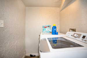 Laundry area with a textured wall, a textured ceiling, and washer and clothes dryer