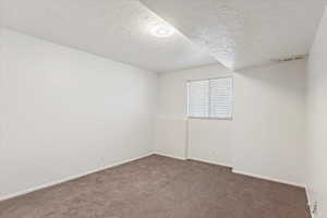 Carpeted empty room featuring baseboards and a textured ceiling