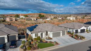 Ranch-style house featuring an attached garage, concrete driveway, roof mounted solar panels, and a residential view