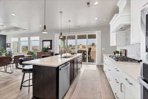Dual tone kitchen with dual tone cabinetry, decorative light fixtures, stainless steel appliances, a breakfast bar, and light stone counters