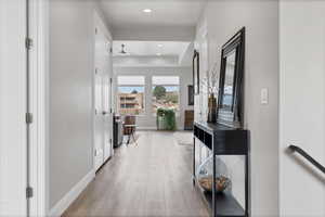 Hallway with light wood-style floors, recessed lighting, and a raised ceiling