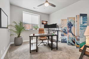 Home office with light colored carpet and ceiling fan