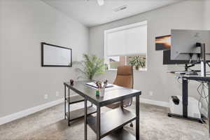 Home office with light colored carpet and baseboards
