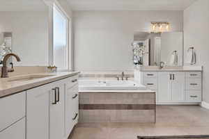 Bathroom featuring two vanities, a bath, and light tile patterned floors
