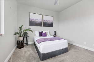 Carpeted bedroom featuring ceiling fan and baseboards