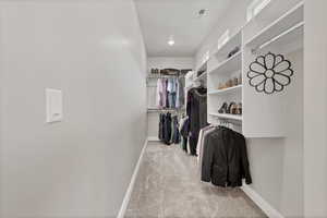 Walk in closet with light colored carpet