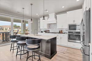 Kitchen featuring stainless steel appliances, an island with sink, pendant lighting, a kitchen breakfast bar, and light wood finished floors