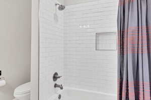 Full bath featuring shower / bathtub combination with curtain and toilet