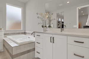 Full bathroom featuring a garden tub, vanity, and recessed lighting