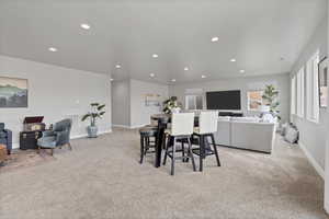 Dining room with light colored carpet and recessed lighting