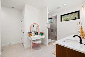 Full bathroom featuring double vanity, a stall shower, and light tile patterned flooring