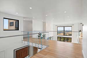 Hallway featuring wood finished floors, healthy amount of natural light, and recessed lighting