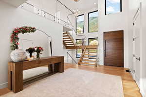Foyer entrance with light wood-style floors, a high ceiling, suspended lighting, and a mountain view