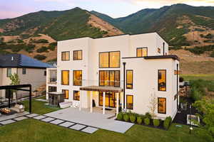 Rear view of house with a mountain view, a lawn, a patio area, and stucco siding