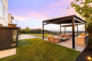 View of green lawn with an outdoor living space with a fire pit and a patio