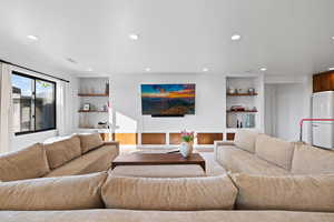 Living area with recessed lighting and built in shelves