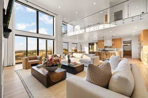 Living area with light wood finished floors, a high ceiling, and recessed lighting