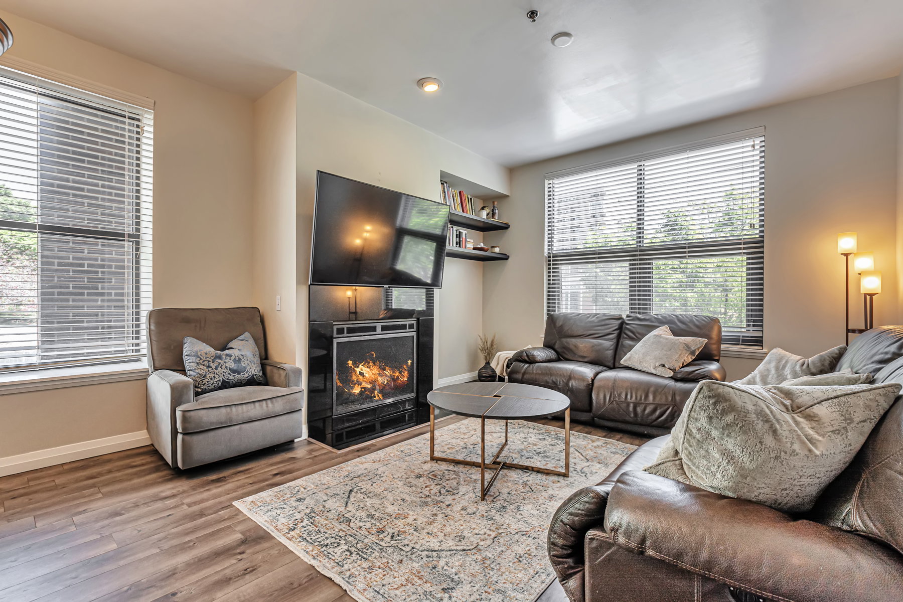 Living room with warm lit fireplace, and recessed lighting