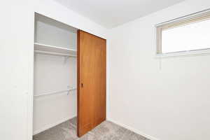 Unfurnished bedroom with light carpet and a closet