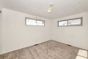 Carpeted empty room featuring baseboards and a smoke detector