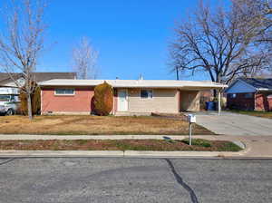 Ranch-style home with brick siding, driveway, an attached carport, and a front lawn