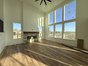 Unfurnished living room with a high ceiling, dark wood finished floors, a fireplace, a ceiling fan, and recessed lighting